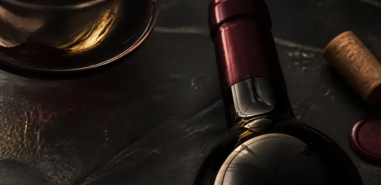 Detaliu de produs cu sticlă, reflexii și accente burgundy.